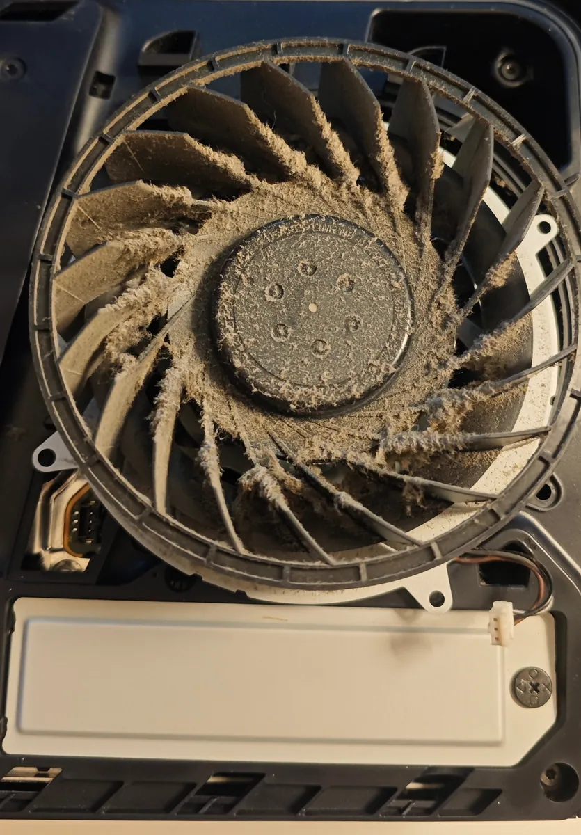PS5 cooling fan inside the console with dust coating every blade and the hub