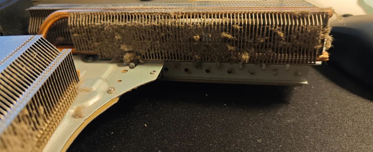 PS5 heatsink removed from the console, with grey dust packed between the fins along its whole length