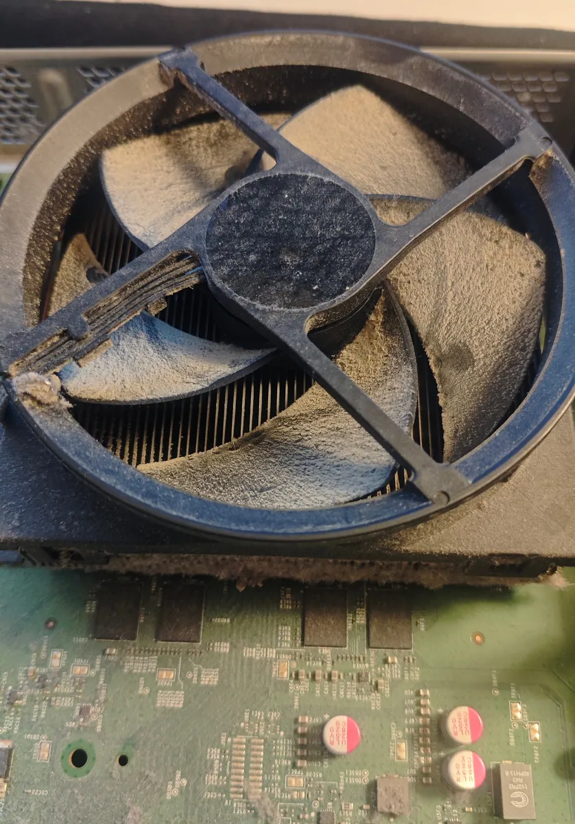 Xbox One fan inside the console with a thick layer of dust on every blade and on the hub