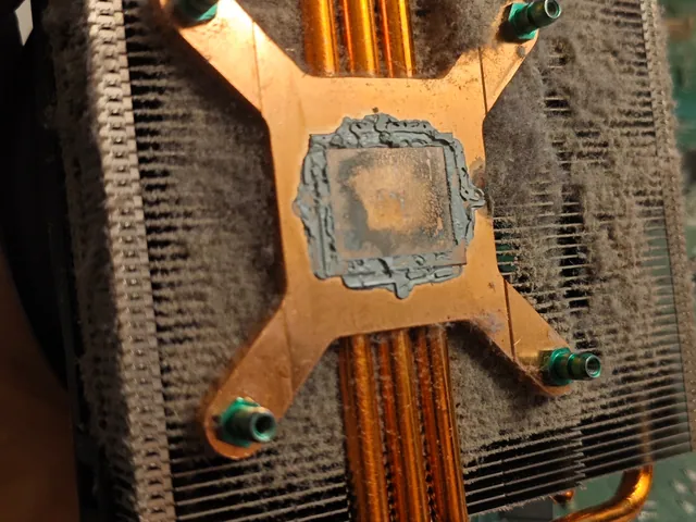 Underside of the Xbox One heatsink: grey dust packed between the fins and dried old thermal paste on the copper base