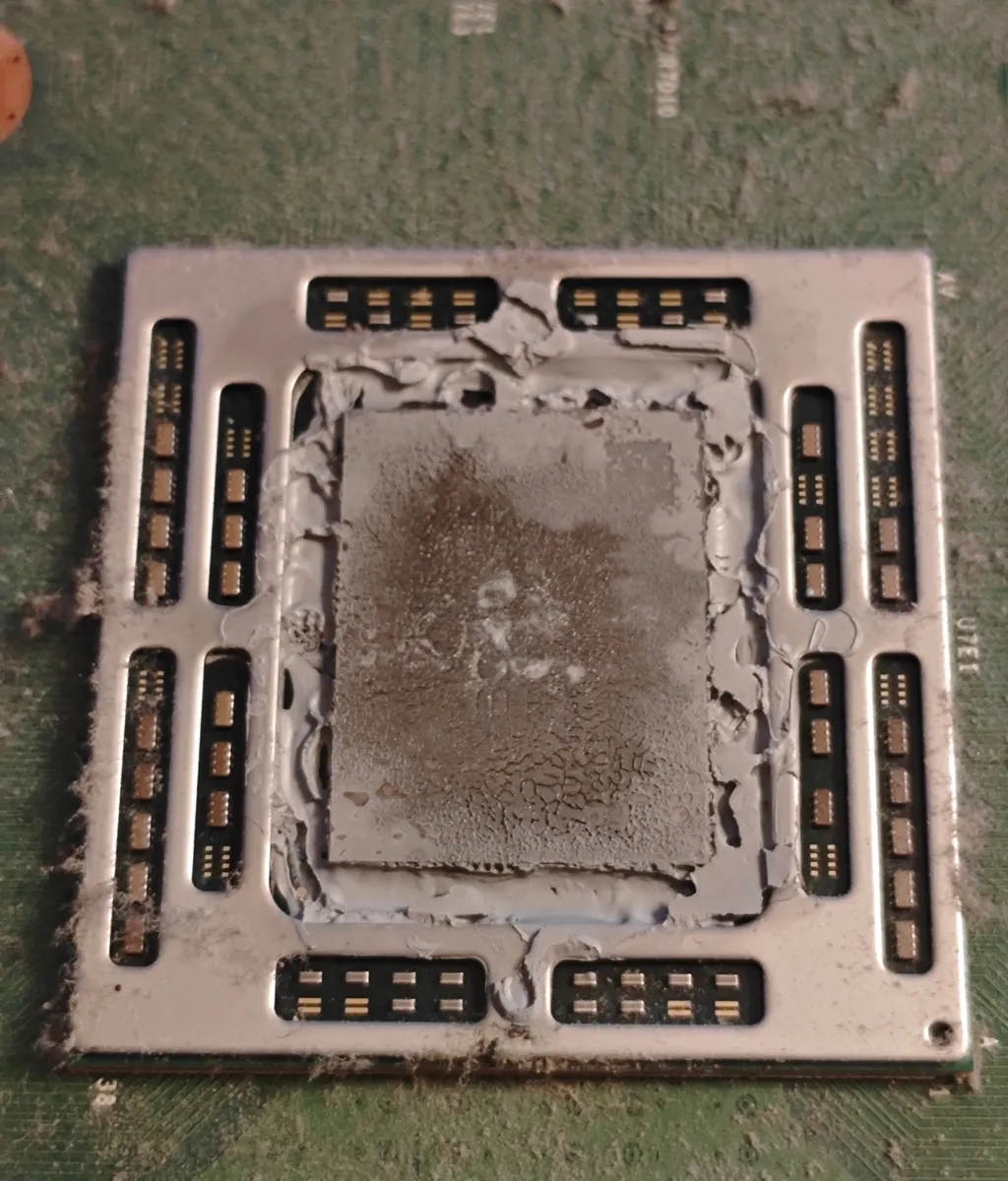Xbox One processor with the heatsink removed, covered in dried, cracked grey thermal paste with dust on top